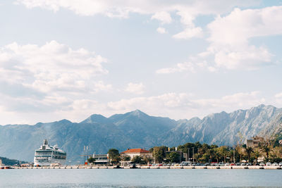 Sailboats in sea by buildings against sky