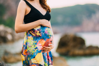 Midsection of woman standing by water