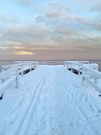 Snow covered pier against sky