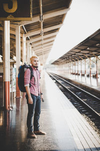 Full length of young man standing at railroad station platform