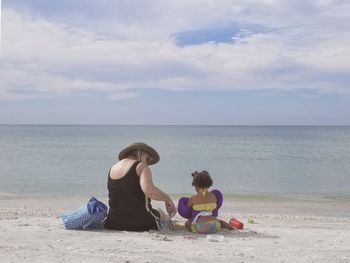 Rear view of friends sitting on beach