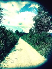 Road amidst field against sky