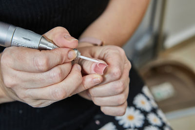 Midsection of woman applying nail