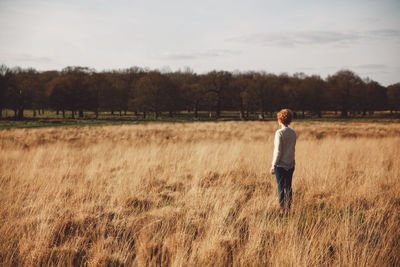 Rear view of young woman standing in grassy field