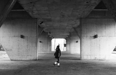 Rear view of man walking under bridge