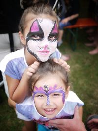 High angle portrait of sisters with face paint on field