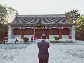 Rear view of a man outside temple against building