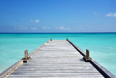 Pier over sea against blue sky