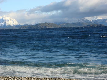 Scenic view of sea and mountains against cloudy sky