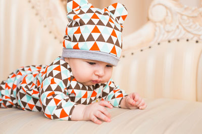 Cute boy looking away while relaxing on bed