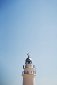 Low angle view of lighthouse by building against clear sky