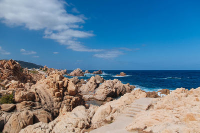 Scenic view of rocky beach against blue sky