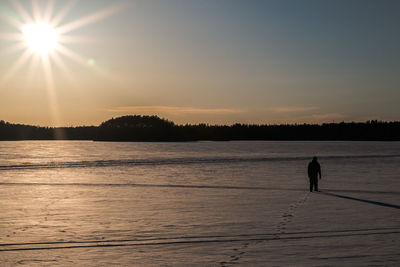 Full length of person standing on frozen lake against sky