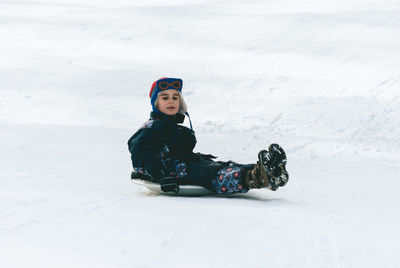 Boy tobogganing on snowy field