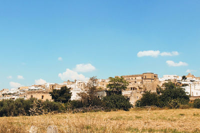 Buildings on field against blue sky