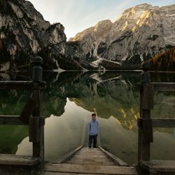 Rear view of man standing by lake against mountain