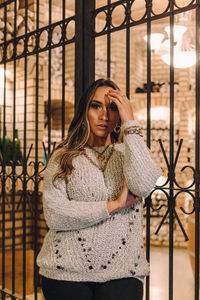 Portrait of beautiful woman standing against gate