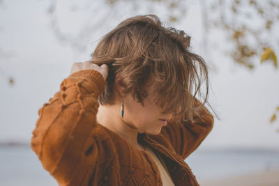 Woman with eyes closed at beach against sky