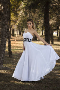 Portrait of beautiful woman on land against trees in forest