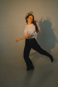 Full length of young woman standing against wall