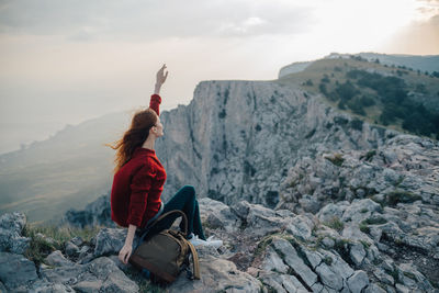 Woman sitting on rock against mountain