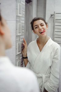 Young woman in bathrobe standing at bathroom