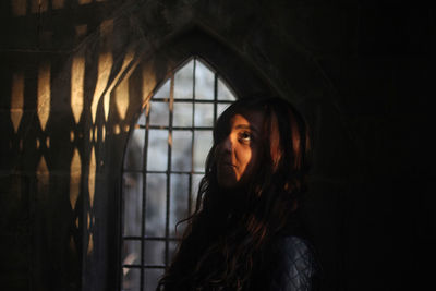 Woman looking up standing against window