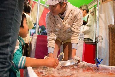 Girl looking at boy by fish tank during goldfish scooping festival