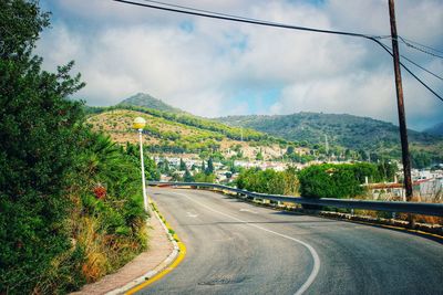 Road amidst trees and mountains against sky