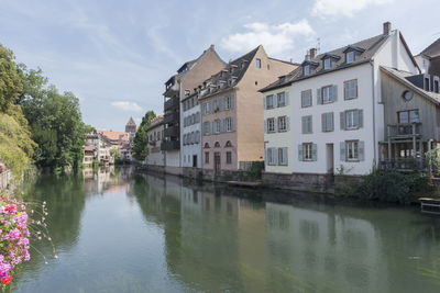 Houses by river in town against sky