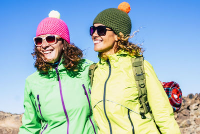 Happy friends wearing sunglasses against clear blue sky