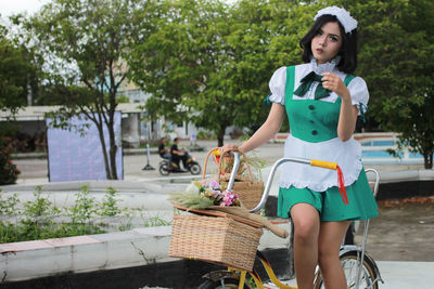 Portrait of woman sitting on bicycle against trees