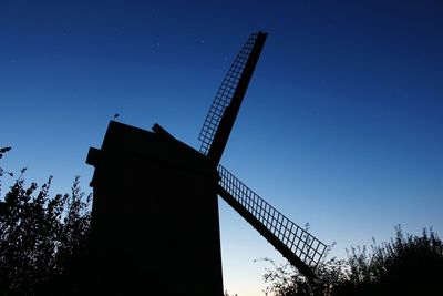 Low angle view of traditional windmill against clear blue sky