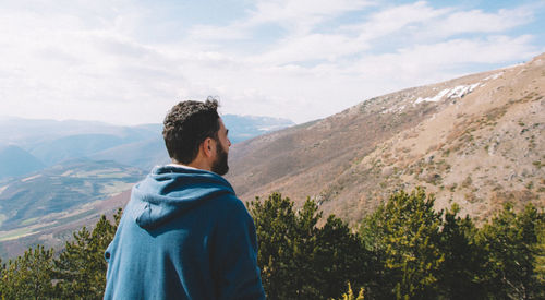 Rear view of man looking at mountain against sky