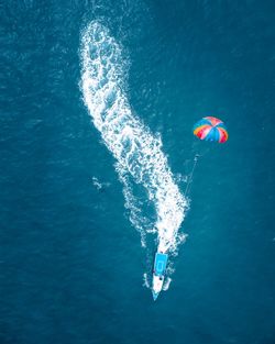 Aerial view of parachute flying over boat in sea