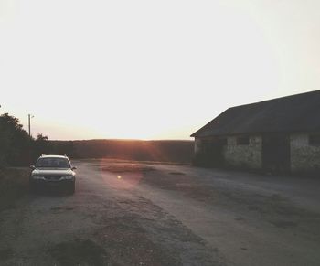 Cars on road against clear sky during sunset