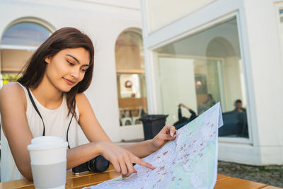 Smiling woman holding map sitting at cafe