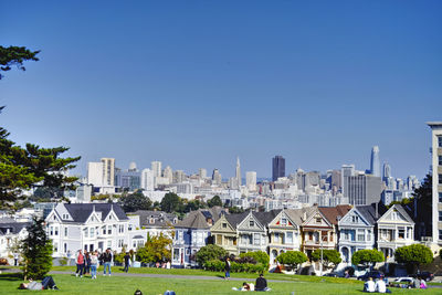 Group of people in front of buildings against clear blue sky