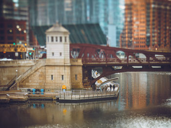 A couple walking their dog under a drawbridge on the chicago riverwalk