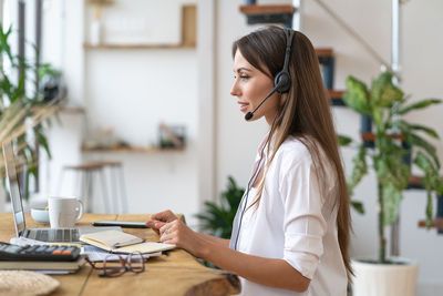 Woman participates in videoconference, wear headphones, communicating with client via video call