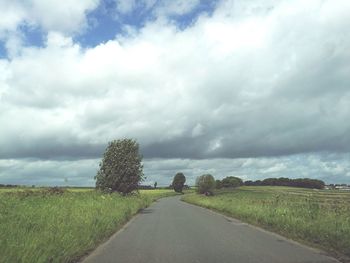 Road amidst field against sky