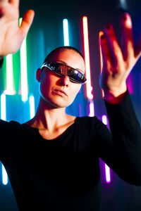 Woman wearing smart glasses gesturing in front of glowing lights