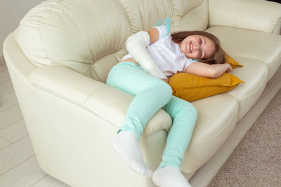 High angle view of girl lying on sofa at home