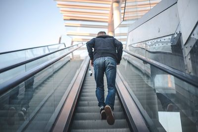 Rear view full length of man on escalator