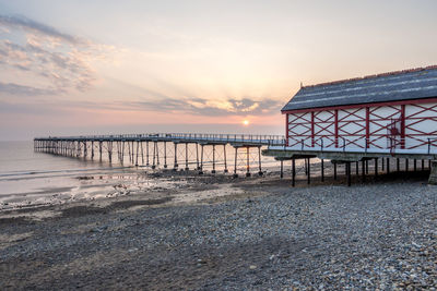 Pier over sea against sky during sunset