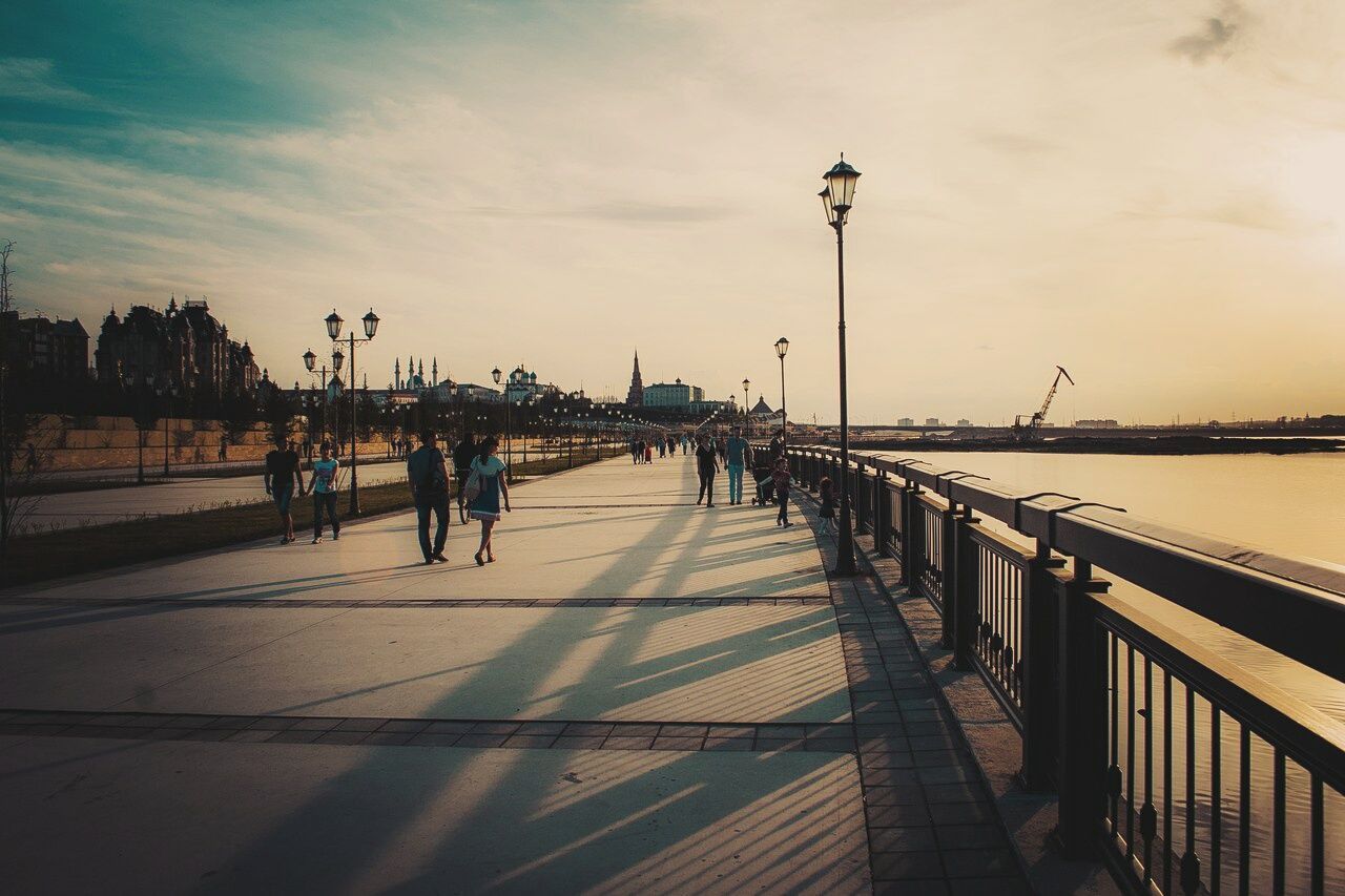 sky, water, men, sea, pier, lifestyles, street light, railing, cloud - sky, leisure activity, the way forward, transportation, person, sunset, walking, nature, silhouette, medium group of people, cloud