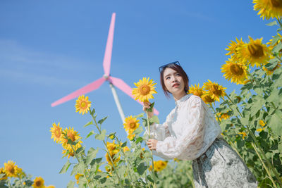 Portrait of woman with sunflower against sky