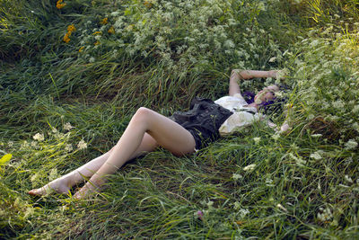 Portrait of a teenage girl with purple hair and an earring in her nose lying in the grass in nature