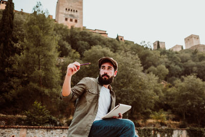 Man writing in book while sitting outdoors