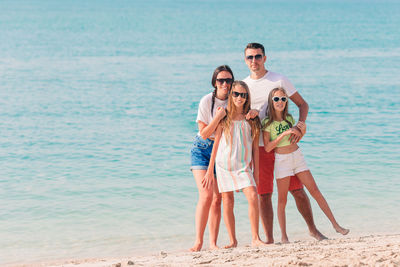 Full length of friends standing on beach